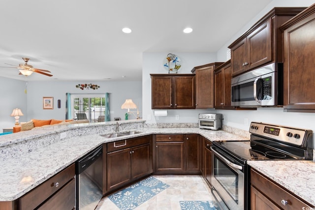 kitchen featuring appliances with stainless steel finishes, a sink, dark brown cabinetry, light stone countertops, and ceiling fan