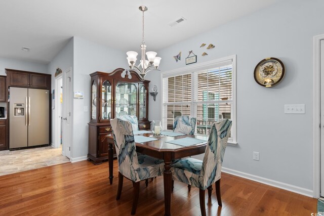 dining room with a chandelier, light wood finished floors, and healthy amount of natural light