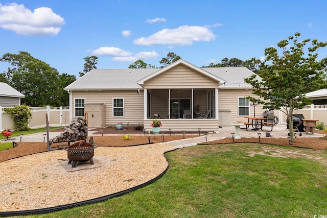back of property with a fire pit, a patio, a sunroom, and metal roof
