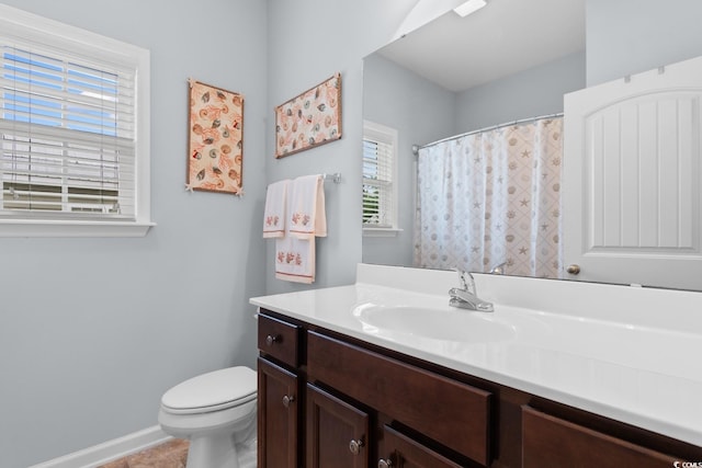 bathroom with plenty of natural light, toilet, vanity, and baseboards