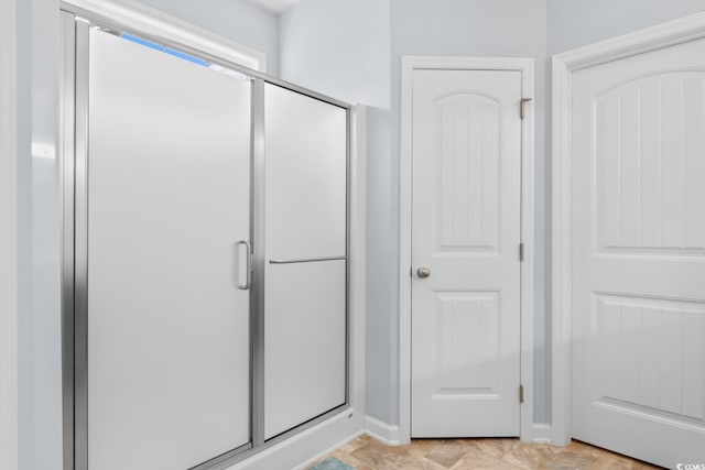 bathroom featuring a shower stall and baseboards