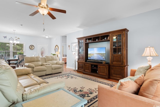 living area featuring a chandelier, ceiling fan, and light wood-style flooring