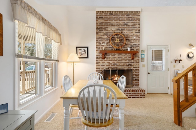 2191 Liberty Cir, Little River, SC 29566 - carpeted dining room featuring a brick fireplace, stairs, baseboards, and a high ceiling