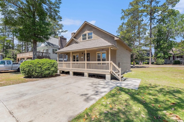 2191 Liberty Cir, Little River, SC 29566 - view of front of house featuring a porch, a front yard, a shingled roof, and a chimney