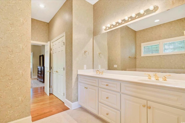 79 Windsor Cir SW, Ocean Isle Beach, NC 28469 - bathroom featuring wallpapered walls, wood finished floors, double vanity, and baseboards