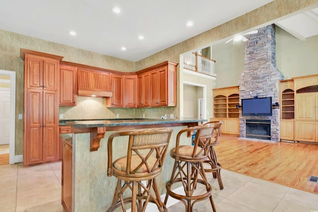79 Windsor Cir SW, Ocean Isle Beach, NC 28469 - kitchen featuring light tile patterned floors, premium range hood, a kitchen bar, recessed lighting, and decorative backsplash