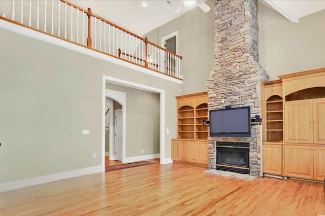 79 Windsor Cir SW, Ocean Isle Beach, NC 28469 - unfurnished living room with a high ceiling, light wood-style floors, a fireplace, baseboards, and arched walkways
