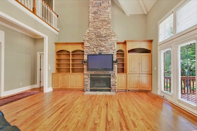 79 Windsor Cir SW, Ocean Isle Beach, NC 28469 - unfurnished living room featuring high vaulted ceiling, a stone fireplace, light wood-style flooring, and baseboards