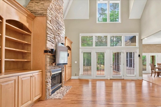 79 Windsor Cir SW, Ocean Isle Beach, NC 28469 - unfurnished living room with a high ceiling, a fireplace, light wood finished floors, french doors, and baseboards