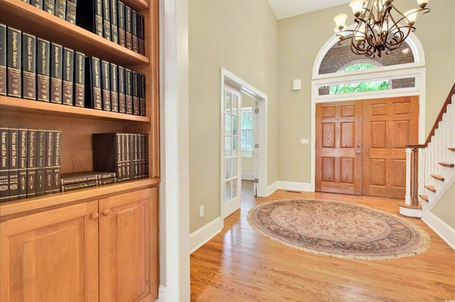 79 Windsor Cir SW, Ocean Isle Beach, NC 28469 - entryway featuring light wood-type flooring, a chandelier, a high ceiling, baseboards, and stairway