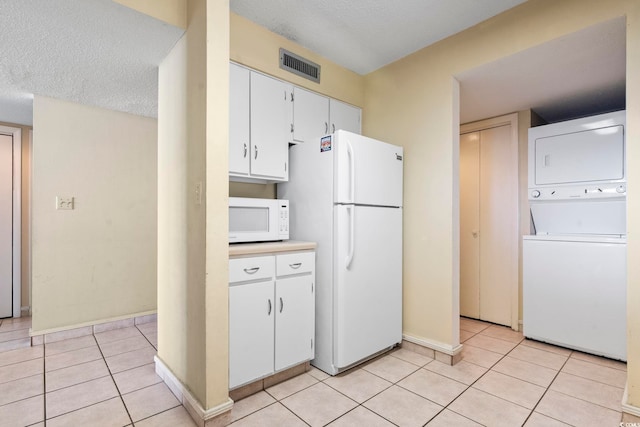 2511 S Ocean Blvd S Unit 1802B, Myrtle Beach, SC 29577 - kitchen with white appliances, stacked washer / dryer, baseboards, light tile patterned floors, and white cabinetry