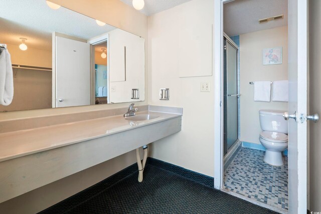 2511 S Ocean Blvd S Unit 1802B, Myrtle Beach, SC 29577 - bathroom featuring toilet, a stall shower, a sink, baseboards, and a textured ceiling