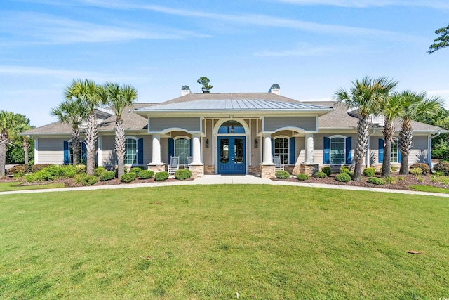 view of front facade with french doors, a front yard, a chimney, and covered porch