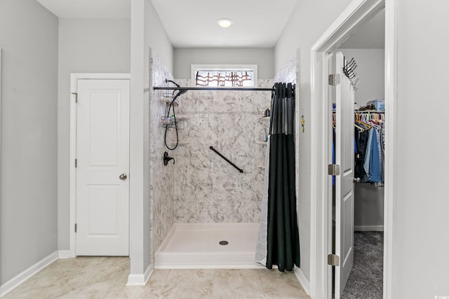 full bathroom with a shower stall, baseboards, a walk in closet, and tile patterned flooring