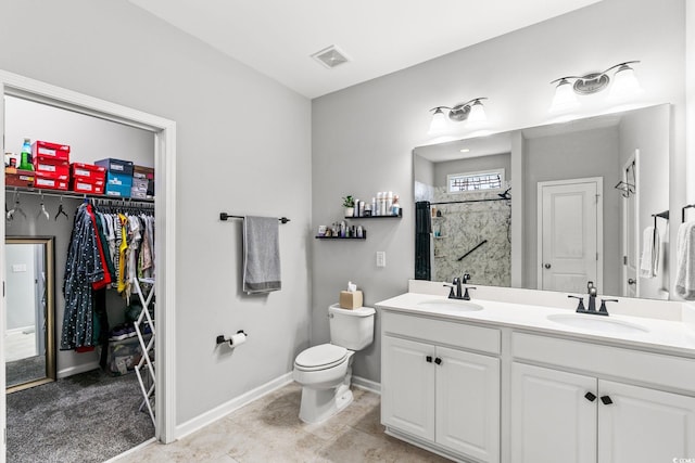 full bath with a walk in shower, toilet, double vanity, baseboards, and a walk in closet