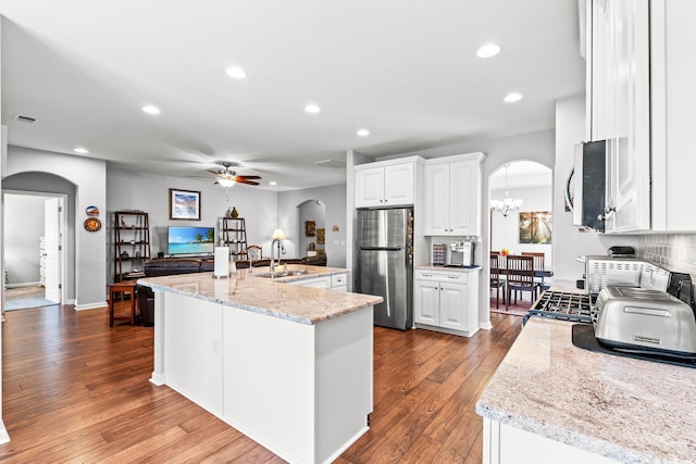 kitchen with arched walkways, appliances with stainless steel finishes, a sink, a ceiling fan, and dark wood-style floors