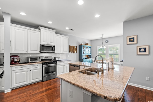 kitchen featuring appliances with stainless steel finishes, a sink, a kitchen island with sink, decorative backsplash, and white cabinetry