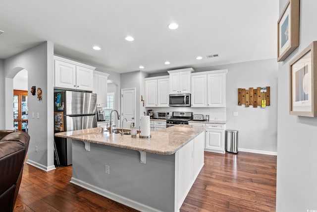 kitchen featuring stainless steel appliances, arched walkways, recessed lighting, baseboards, and dark wood-style floors