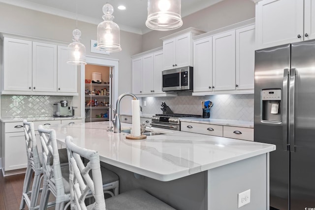 kitchen featuring stainless steel appliances, a sink, tasteful backsplash, white cabinets, and a kitchen island with sink