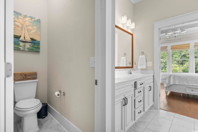 bathroom featuring marble look tile flooring, toilet, vanity, and ensuite bath