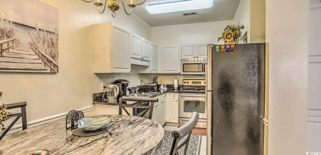 9780 Leyland Dr Unit 112, Myrtle Beach, SC 29572 - kitchen with stainless steel appliances, white cabinets, dark countertops, wood finished floors, and a sink