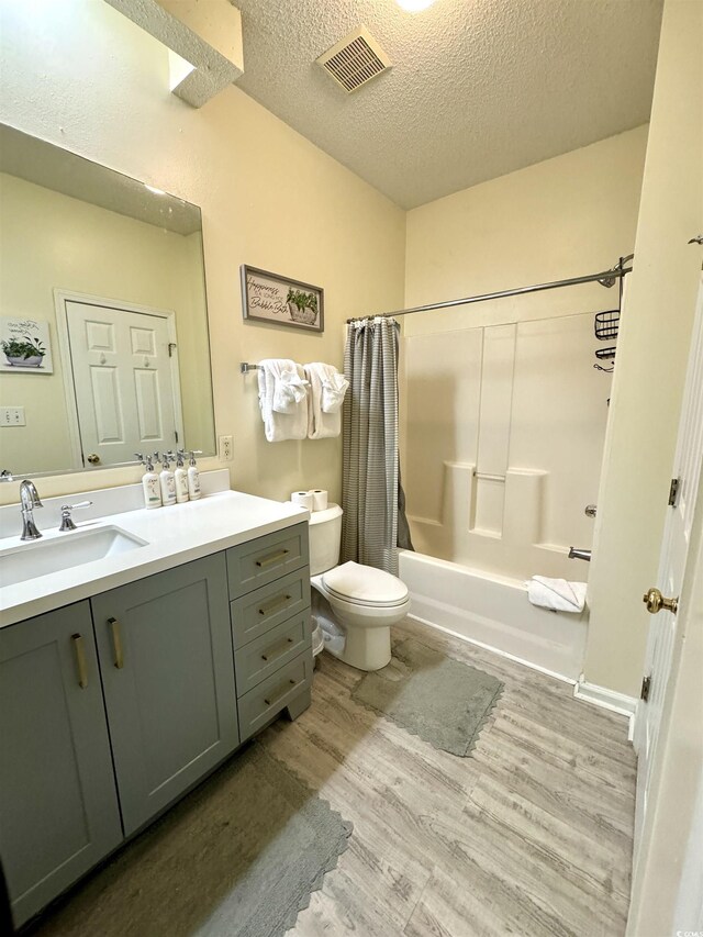 9780 Leyland Dr Unit 112, Myrtle Beach, SC 29572 - bathroom featuring wood finished floors, a textured ceiling, toilet, shower / bathtub combination with curtain, and vanity