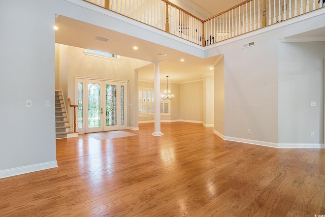 78 Oakmont Dr, Pawleys Island, SC 29585 - unfurnished living room with decorative columns, a chandelier, ornamental molding, stairs, and a towering ceiling