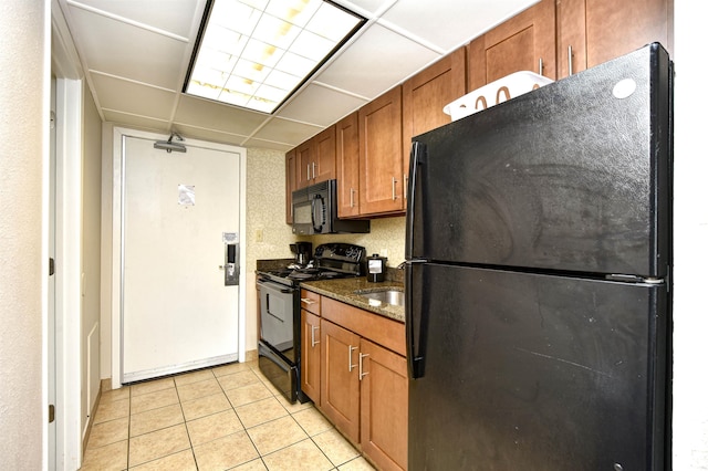 1105 S Ocean Blvd Unit 1144, Myrtle Beach, SC 29577 - kitchen featuring black appliances, brown cabinetry, light tile patterned flooring, dark stone countertops, and a drop ceiling