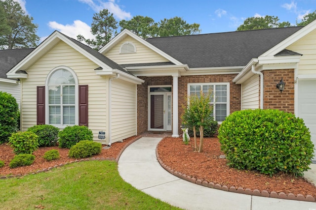 ranch-style house with brick siding, an attached garage, and a shingled roof