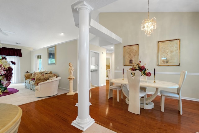 dining space featuring decorative columns, wood finished floors, baseboards, a chandelier, and a ceiling fan