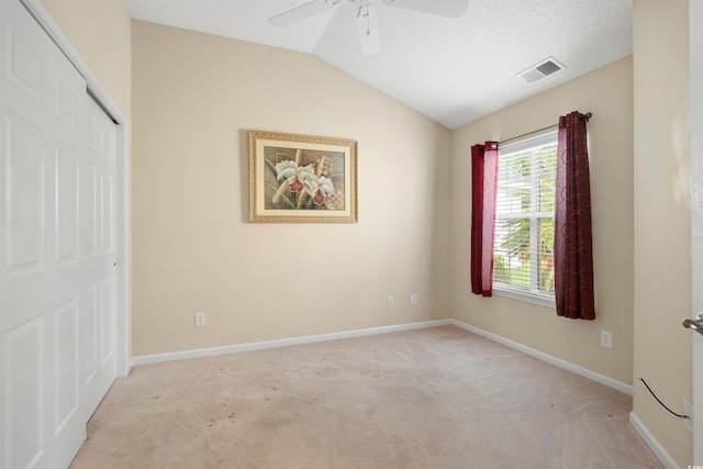 unfurnished bedroom featuring light colored carpet, vaulted ceiling, a closet, baseboards, and ceiling fan