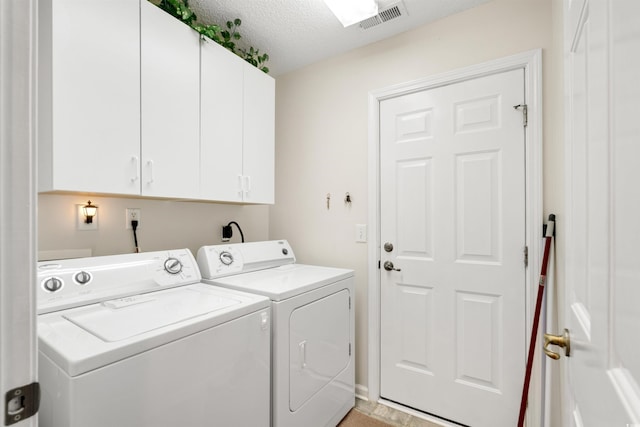 clothes washing area with cabinet space, washing machine and clothes dryer, and a textured ceiling