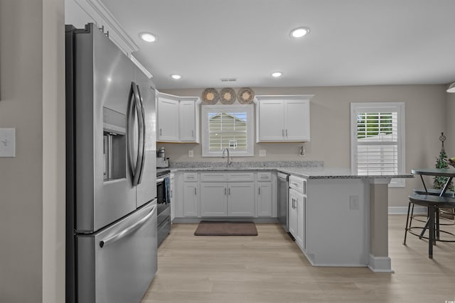 1307 Collins Park St, Conway, SC 29526 - kitchen with appliances with stainless steel finishes, a peninsula, white cabinets, a breakfast bar, and light stone counters