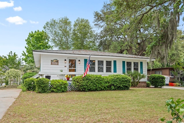 view of front of house with a front yard, driveway, and metal roof