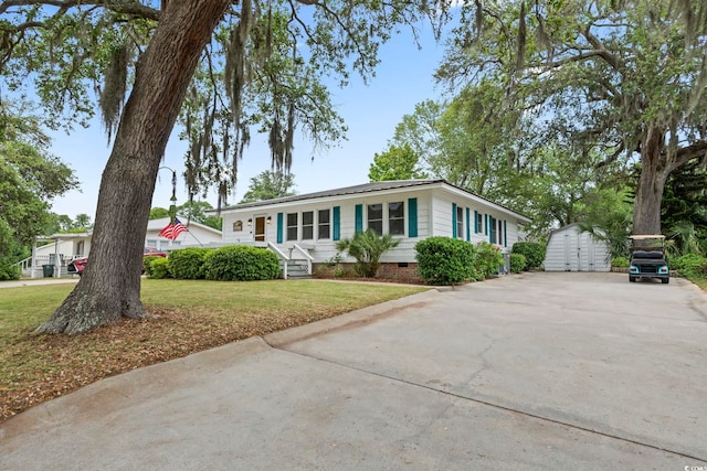 single story home featuring a storage unit, crawl space, an outbuilding, a front lawn, and driveway
