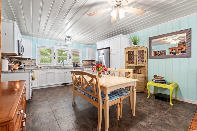 dining space with ceiling fan and dark tile patterned floors