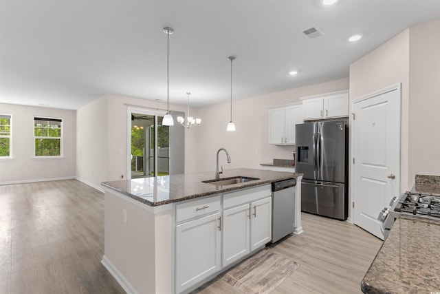 736 Flowering Branch Ave, Little River, SC 29566 - kitchen with appliances with stainless steel finishes, light wood-style flooring, a kitchen island with sink, white cabinets, and dark stone counters