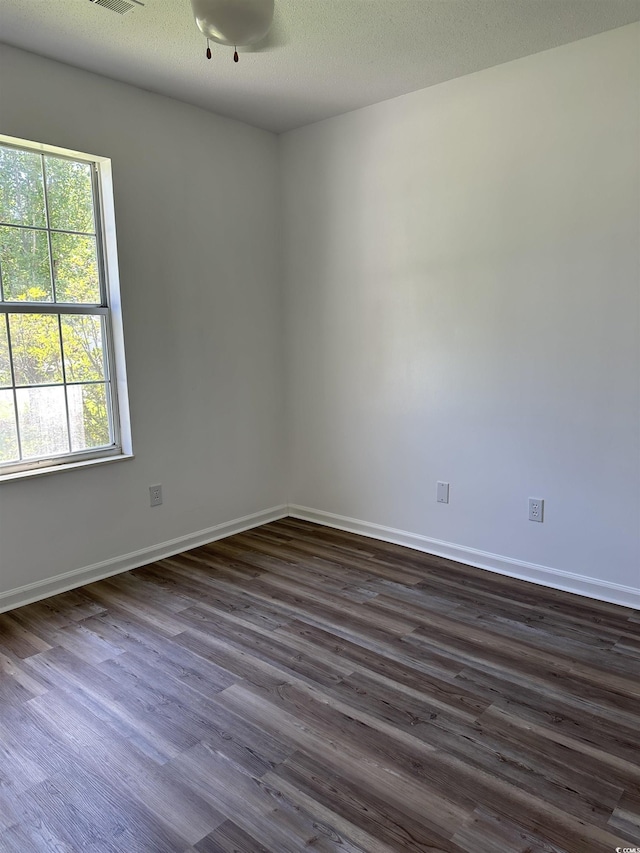 unfurnished room with dark wood-style flooring, plenty of natural light, and baseboards
