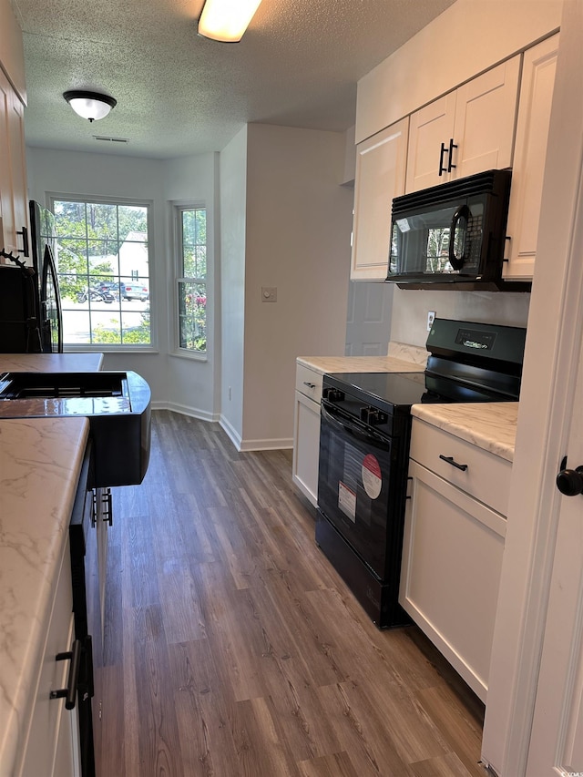 kitchen featuring black appliances, dark wood-type flooring, white cabinetry, baseboards, and a textured ceiling