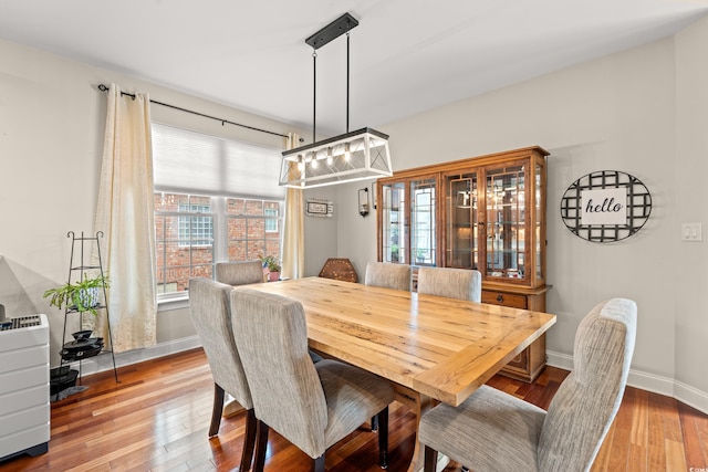 dining space featuring hardwood / wood-style flooring, a chandelier, and baseboards