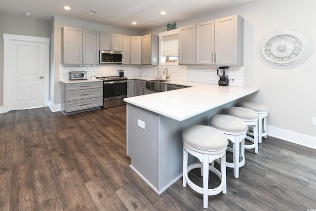 113B 11th Ave S, Surfside Beach, SC 29575 - kitchen featuring appliances with stainless steel finishes, gray cabinetry, a breakfast bar, dark wood-style flooring, and recessed lighting