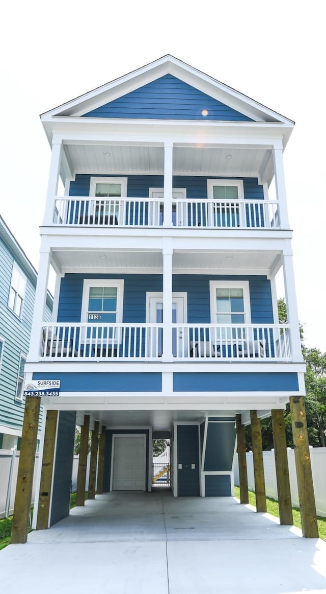 113B 11th Ave S, Surfside Beach, SC 29575 - coastal inspired home with a carport, a balcony, concrete driveway, and an attached garage