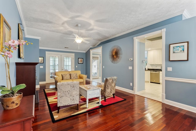 living area with hardwood / wood-style floors, a textured ceiling, a ceiling fan, ornamental molding, and baseboards