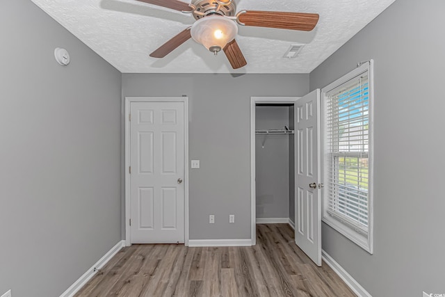 unfurnished bedroom featuring wood finished floors, a textured ceiling, a closet, and baseboards