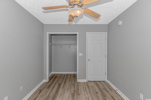 unfurnished bedroom with a textured ceiling, wood finished floors, a closet, baseboards, and a ceiling fan