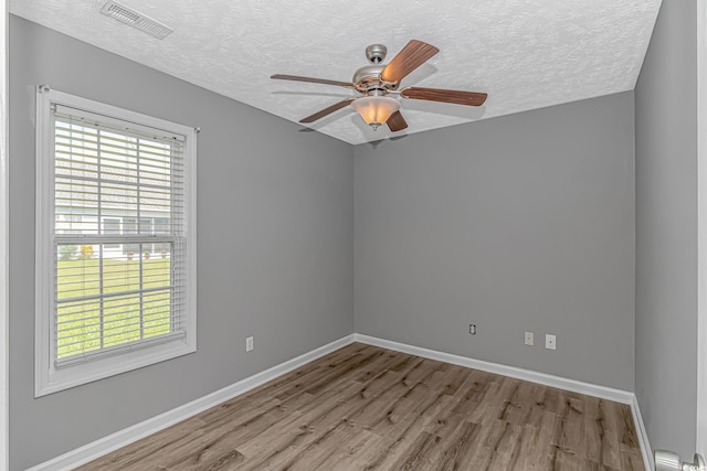 empty room with wood finished floors, a textured ceiling, baseboards, and a ceiling fan