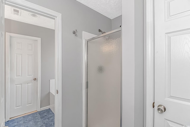 bathroom with a shower stall and a textured ceiling
