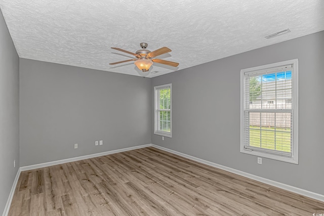 empty room featuring wood finished floors, a ceiling fan, a textured ceiling, and baseboards