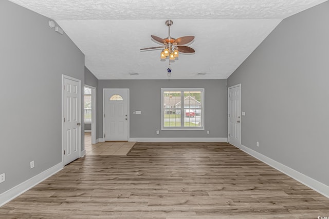 entryway with a textured ceiling, a ceiling fan, lofted ceiling, wood finished floors, and baseboards
