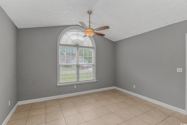 empty room featuring lofted ceiling, a ceiling fan, a textured ceiling, light tile patterned flooring, and baseboards